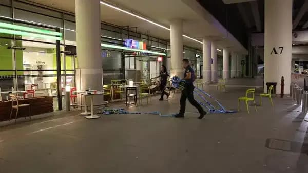 İzmir Adnan Menderes Havalimanı terminal binası önünde bıçaklı saldırı olayının ardından olay yeri inceleme şeridi çeken ve inceleme yapan polis ekipleri.